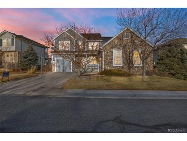 Charming two-story home with a stone facade and gray siding, set against a colorful sky at dusk at 13694 Cherry St, Thornton, CO 80602