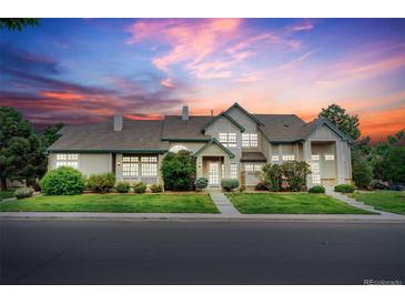 Inviting two-story home with a well-manicured lawn and a charming front porch, set against a beautiful sunset sky at 10087 E Hawaii Pl, Aurora, CO 80247