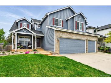 Charming two-story home with blue siding, brick accents, three-car garage and a well-manicured lawn at 14194 W Amherst Ave, Lakewood, CO 80228
