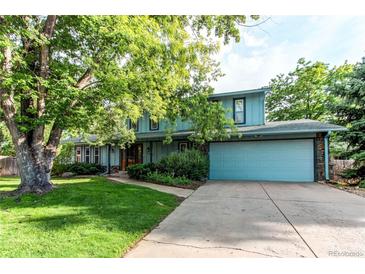 Charming two-story home featuring blue siding, mature trees, a landscaped yard, and an attached two-car garage at 11682 E Iowa Ave, Aurora, CO 80012