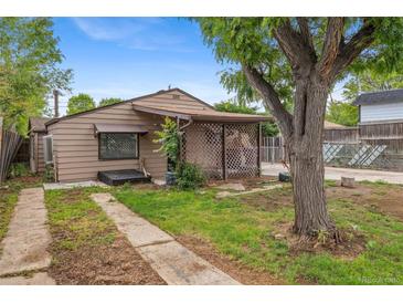 Cozy single-story home with brown siding, mature tree, and small porch area at 530 S Quitman St, Denver, CO 80219
