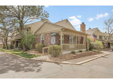 Charming brick home featuring a covered front porch and well-maintained landscaping at 7291 E Bentley Cir, Centennial, CO 80122