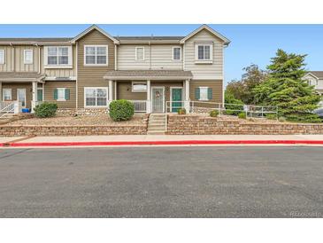 Inviting townhouse featuring a charming front porch and manicured landscaping for great curb appeal at 14700 E 104Th Ave # 2802, Commerce City, CO 80022