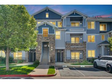 Inviting townhome featuring stone accents, a well-maintained lawn, and assigned parking spaces at 5255 Memphis St # 317, Denver, CO 80239