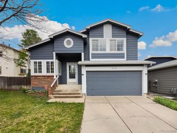 Charming two-story home features a gray exterior, attached garage, and well-maintained front yard at 8536 S Upham Way, Littleton, CO 80128