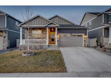 Charming home with a gray exterior, stone accents, a well-maintained lawn, and a two-car garage at 6905 Fraser Cir, Frederick, CO 80530