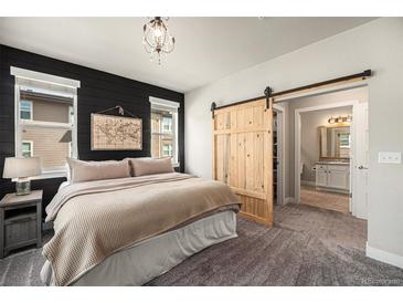 This is a main bedroom with dark accent wall and barn door to en suite bathroom at 15274 W 64Th Ln # 206, Arvada, CO 80007