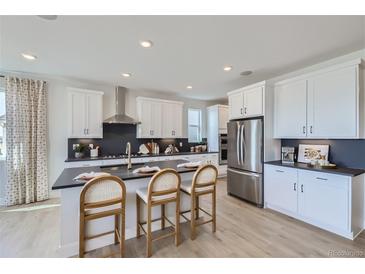 Bright kitchen featuring stainless steel appliances, a dark counter island with seating and light wood floors at 4110 Grand Lake St, Brighton, CO 80601
