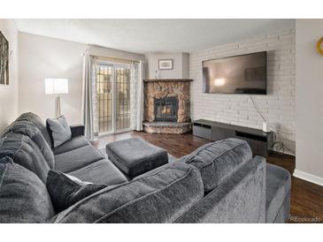 Cozy living room features stone fireplace, exposed brick, and sliding door to backyard at 1060 S Parker Rd # 19, Denver, CO 80231