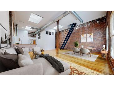 Bright open-concept living area features exposed brick, ductwork, skylights, stairs, and hardwood floors at 1510 Wazee St # 3, Denver, CO 80202