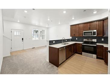 Modern kitchen features stainless appliances, wooden cabinets, and beautiful tile backsplash at 17117 W 91St Ln, Arvada, CO 80007