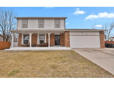 Charming two-story home featuring a brick facade, covered porch with benches, and an attached two-car garage at 9135 Bellaire St, Thornton, CO 80229