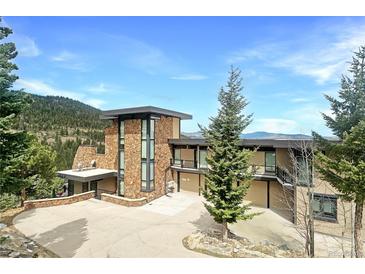 Stunning stone home boasts a modern design with expansive windows and a spacious driveway at 180 Outpost Ln, Evergreen, CO 80439