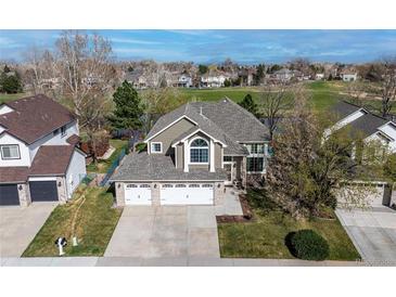 Beautiful home showcasing a manicured front yard, a three car garage and large windows at 6802 Poppy Ct, Arvada, CO 80007