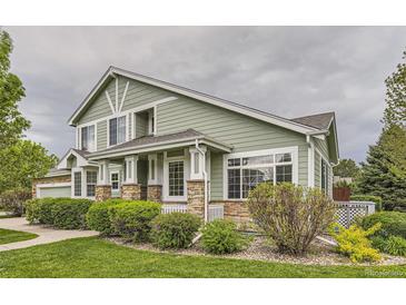 Inviting green home exterior featuring stone accents, manicured lawn, and beautiful landscaping at 7498 W Saratoga Pl, Littleton, CO 80123