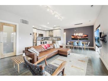 Open-concept living room featuring a modern kitchen, dining area, hardwood floors, and comfortable leather seating at 3644 Pinedale St, Boulder, CO 80301