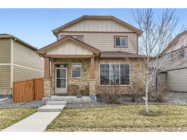 Charming two-story home featuring stone accents, manicured lawn, and inviting front porch at 11769 Lovegrass Dr, Parker, CO 80138