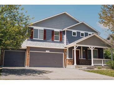 Charming two-story home with a three car garage, covered porch, gray siding and brick accents at 3725 S Nepal St, Aurora, CO 80013