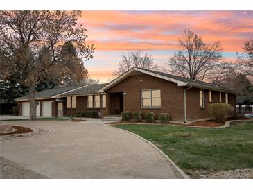 Inviting single-story brick home featuring a circular driveway and professional landscaping at 1324 State Highway 66, Longmont, CO 80504