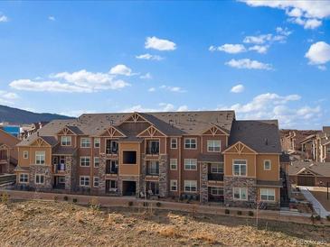 Low-angle shot shows an apartment building with a blue sky, brown siding, and decorative stonework at 9962 W Victoria Pl # 106, Littleton, CO 80127