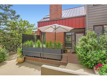 Inviting patio area with privacy planters, a large umbrella, and a brick exterior at 780 Walnut St # A, Boulder, CO 80302