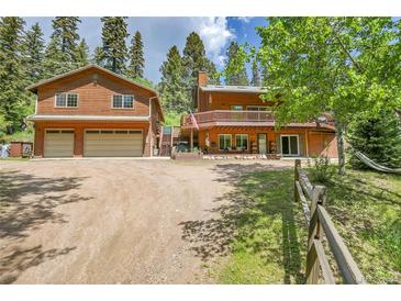 Inviting cabin-style home featuring wood siding, a spacious deck, and an attached two-car garage with large driveway at 11182 S Barney Gulch Rd, Conifer, CO 80433