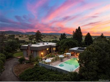 Stunning twilight aerial view of home with a pool and mountain views in the background at 3675 S Perry Park Rd, Sedalia, CO 80135