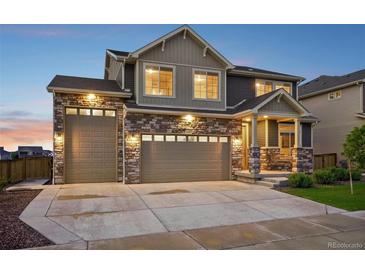 Beautiful home with a stone and siding exterior, three-car garage, and a welcoming front porch at 16595 E 110Th Ave, Commerce City, CO 80022