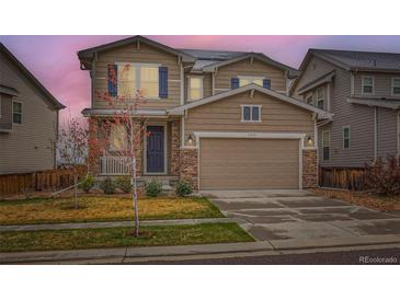 Two-story home with a two-car garage, stone accents, blue shutters, and a well-manicured front yard at 17859 E 108Th Pl, Commerce City, CO 80022