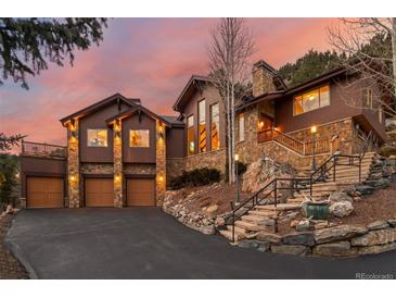 Beautiful home exterior featuring stone accents, a three-car garage, and a well-maintained driveway at 127 Granite Way, Evergreen, CO 80439