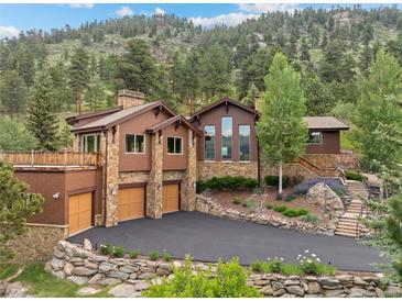 Beautiful exterior featuring a stone-and-siding design, manicured landscaping, and an expansive driveway with mountain backdrop at 127 Granite Way, Evergreen, CO 80439