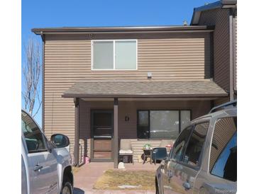 Inviting townhome featuring a covered front porch, outdoor seating, and neutral siding with dark trim details at 473 N Banner St # D, Elizabeth, CO 80107