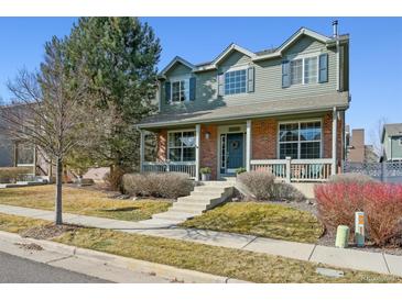 Charming two-story home with brick and siding, a covered porch, and manicured landscaping at 12453 Knox Ct, Broomfield, CO 80020