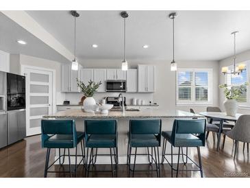 Bright kitchen featuring a large island with seating, pendant lighting, and stainless steel appliances at 16197 Paris Way, Brighton, CO 80602