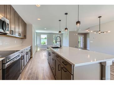 Modern kitchen features stainless appliances, quartz counters, dark cabinets, and island with pendant lighting at 3420 N Steele St, Denver, CO 80205