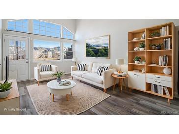 Bright living room featuring a comfy sofa, large windows, and stylish wood floors at 3738 Rosewalk Ct, Highlands Ranch, CO 80129