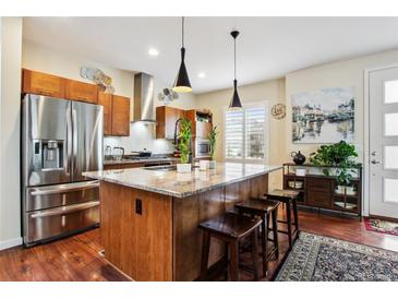 Bright kitchen features a large island with seating, stainless steel appliances, and wood cabinetry at 3379 Cranston Cir, Littleton, CO 80126