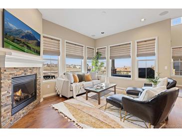 Comfortable living room featuring a brick fireplace, large windows, and stylish furniture at 9581 Firenze Way, Highlands Ranch, CO 80126