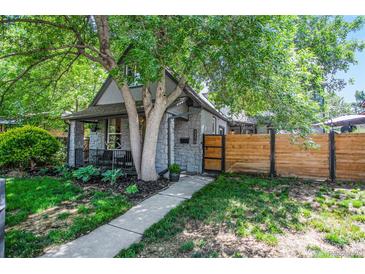 Charming home with gray stone facade, manicured front yard, mature trees, and a modern wood fence at 4570 Irving St, Denver, CO 80211