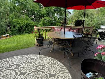 Inviting back deck features comfortable seating, a dining table, and a well-maintained lawn at 18655 E Garden Pl, Aurora, CO 80015