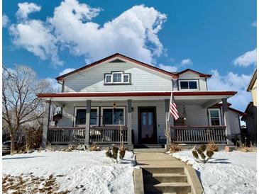 Two-story home with a large front porch and snowy yard at 395 Longspur Dr, Brighton, CO 80601