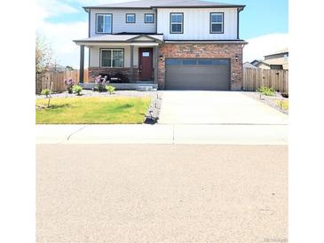 Two-story home with a brick-accented facade, covered porch, and well-manicured lawn and front yard at 13315 Xanthia St, Thornton, CO 80602