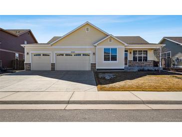 Charming single-Gathering home features a three-car garage and manicured front yard on a sunny day at 56582 E 23Rd Ave, Strasburg, CO 80136