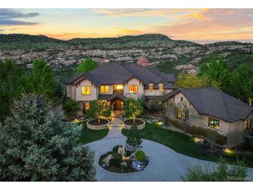 Stunning exterior elevation of grand home, with manicured front yard and mountain views at sunset at 9650 S Cougar Rd, Littleton, CO 80127