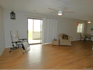 Bright living room featuring hardwood floors, ceiling fan, sliding glass door, and comfortable seating at 2201 Sable Blvd # 1007, Aurora, CO 80011