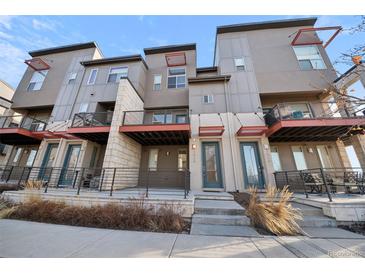 Modern townhome showcases stucco and stone exterior with private patio and sleek, black metal railings at 7928 E 54Th Pl, Denver, CO 80238
