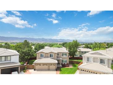 Stunning home with a two-car garage, manicured lawn and beautiful mountain views in the background at 9169 Fox Fire Way, Highlands Ranch, CO 80129