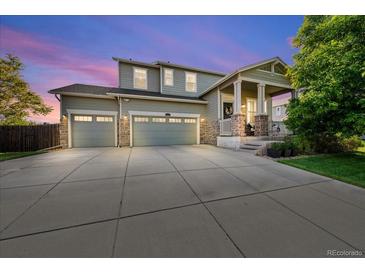Charming two-story home showcasing a manicured lawn and a spacious three-car garage with stone accents on the facade at 12972 Uinta Ct, Thornton, CO 80602