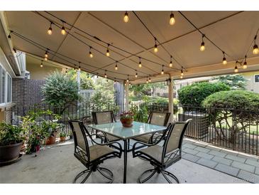 Inviting covered patio with string lights, table, and chairs, perfect for outdoor dining and entertaining at 6937 E Girard Ave, Denver, CO 80224