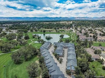 Stunning aerial view of a golf course community with a pond and mountain backdrop at 2951 W Riverwalk Cir # N, Littleton, CO 80123